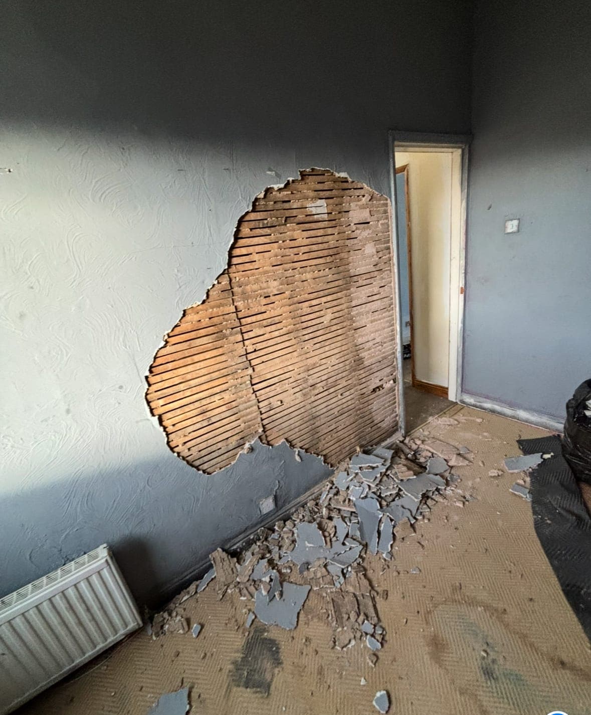 Blown plaster stripped back to the brickwork on a living room wall, before replastering