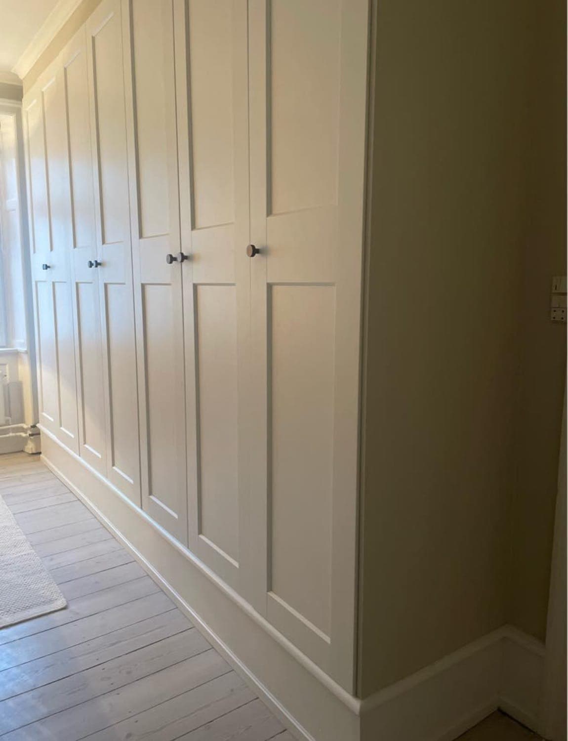 Cream shaker-style fitted wardrobes running along a bedroom wall