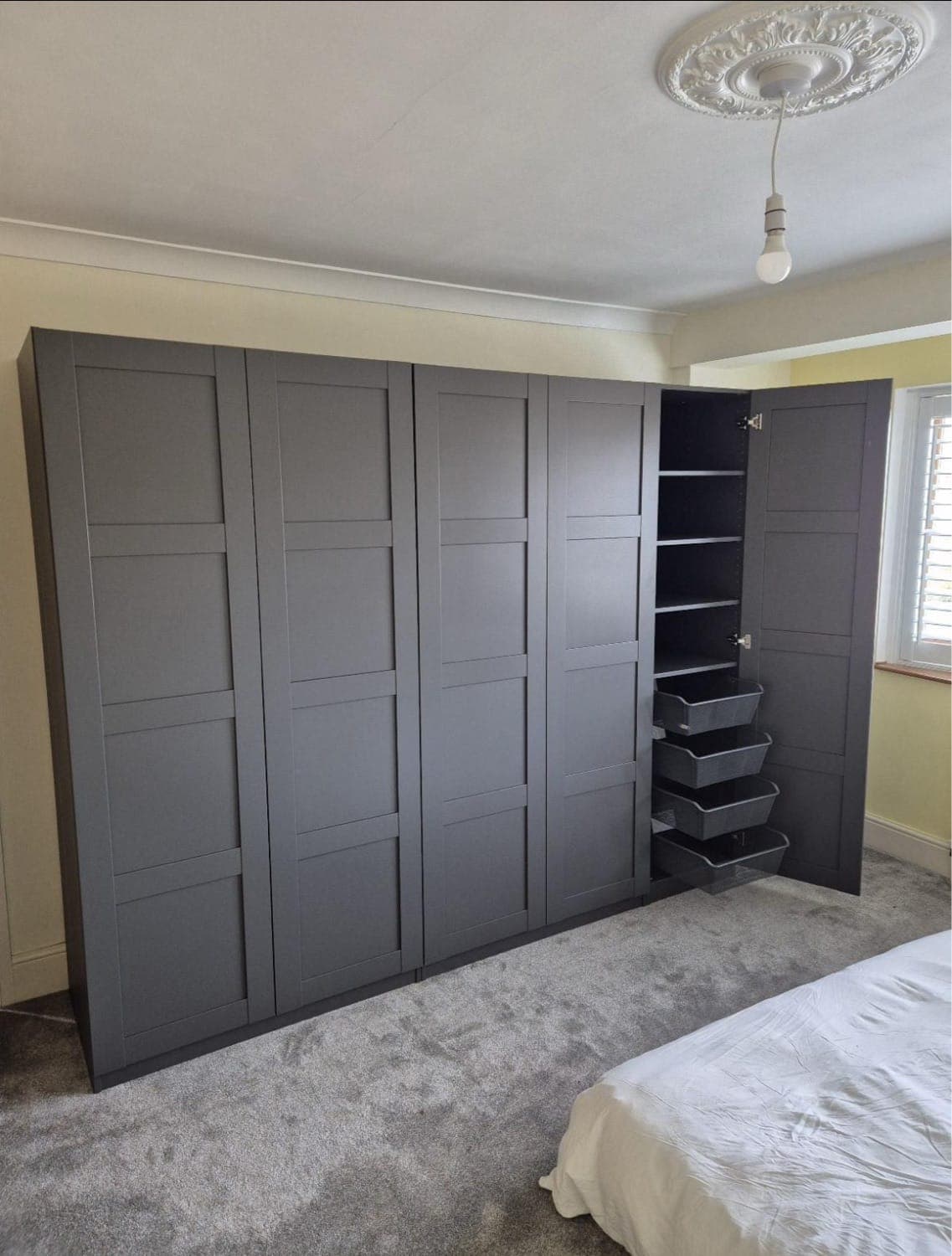 Fitted wardrobes with dark grey shaker doors, one open to show shelving and drawers