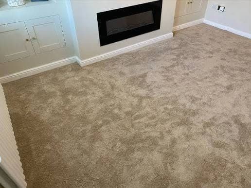 Living room with new grey carpet, white walls and a wall-mounted electric fire