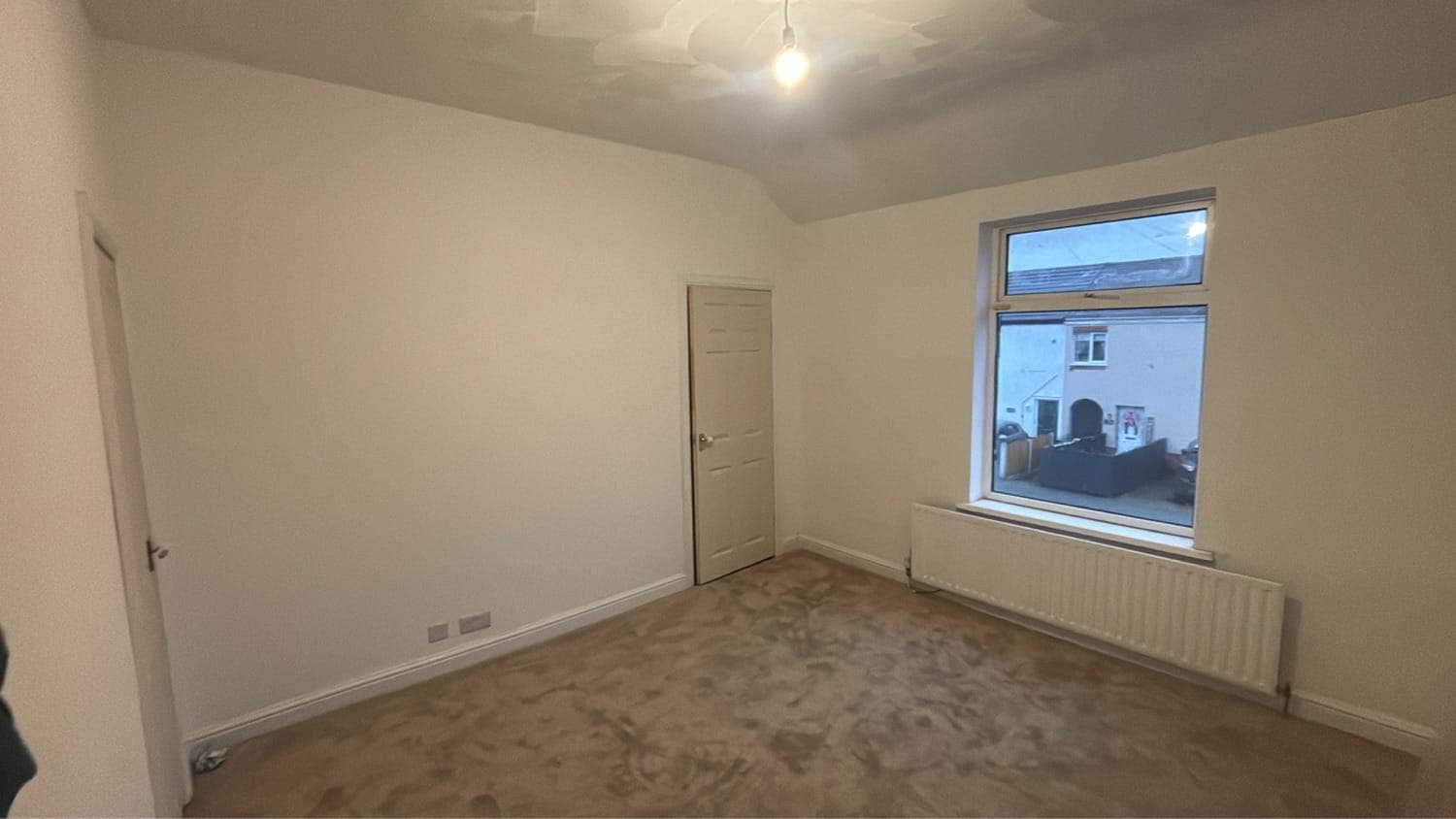 Room repainted throughout in white with new carpet fitted, looking towards the window