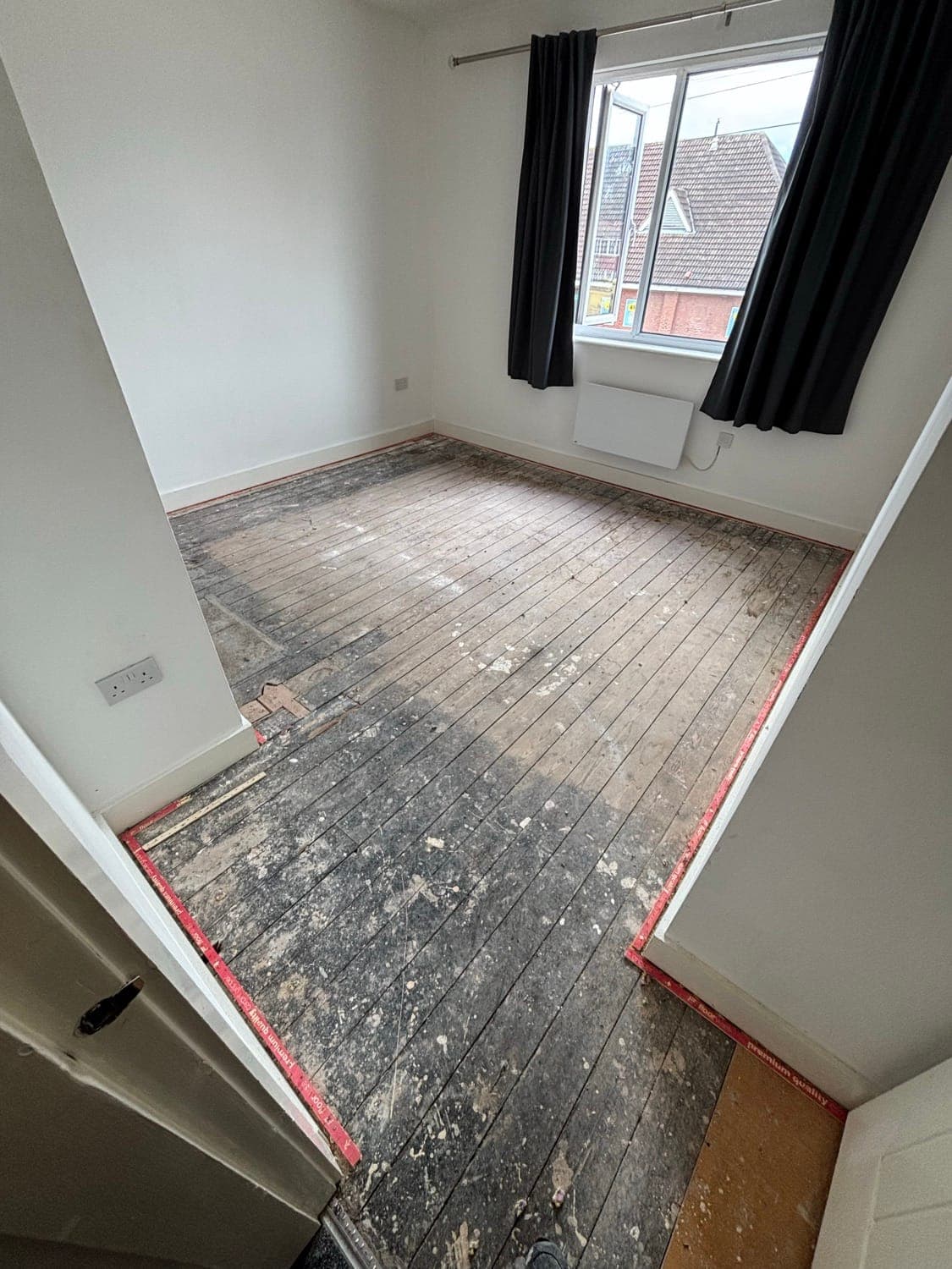 The same bedroom before the carpet, with bare floorboards and gripper rods along the walls