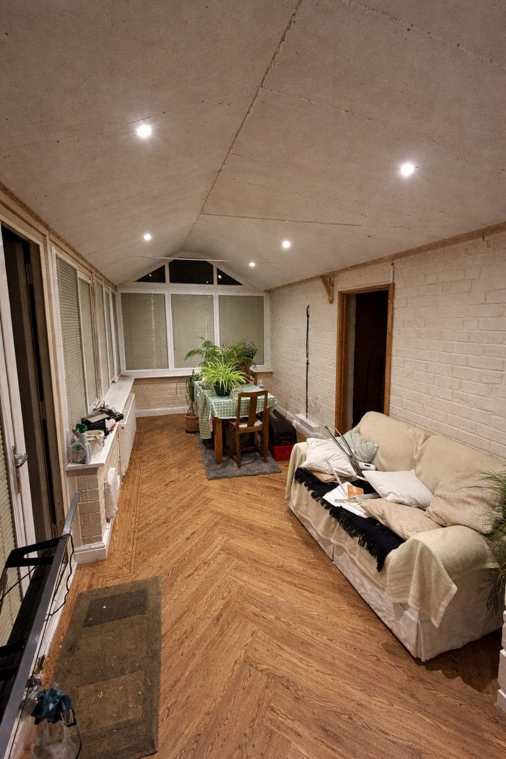 Conservatory with herringbone LVT flooring and a new solid ceiling with spotlights, furnished with sofas and plants