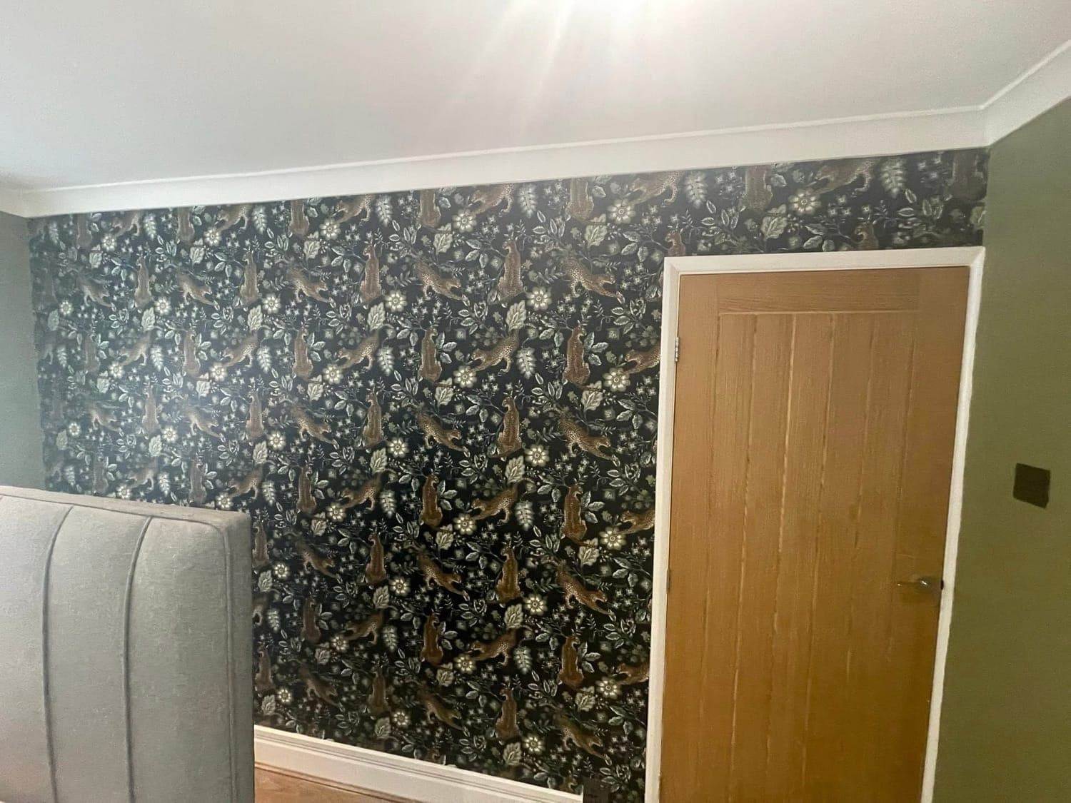Feature wall hung with dark floral wallpaper beside a newly fitted oak door