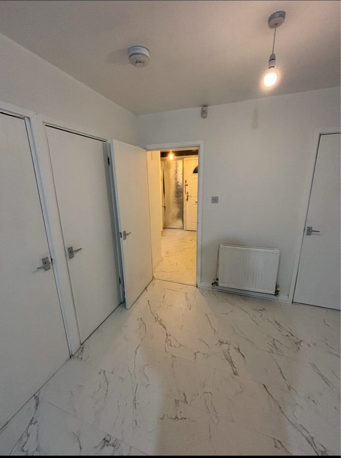Hallway with marble-effect vinyl flooring, white walls and newly painted doors
