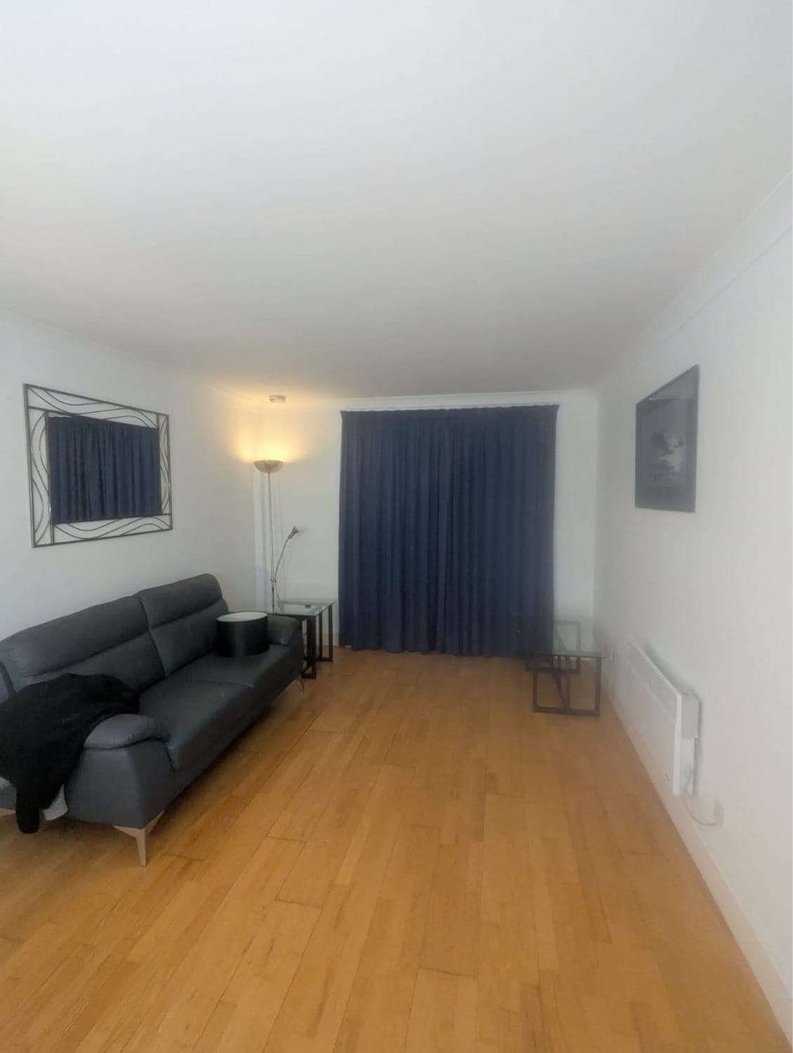 Living room with new oak laminate flooring, freshly painted white walls and navy curtains